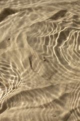 Water texture with shadows on sea beach sand