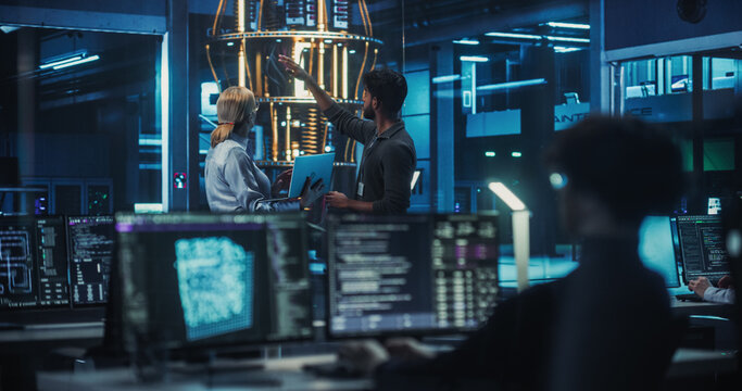 Engineers Collaborating on Quantum Computer Development, Analyzing Data on Advanced AI Software in an Industrial Laboratory. Diverse Team Focusing on Innovation and Technology Breakthroughs
