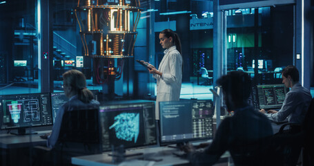Portrait of a Female Researcher Standing Before a Powerful Quantum Computer, Using a Tablet Computer to Monitor Digital Data. Smart Woman  is Analyzing Results and Parameters Online