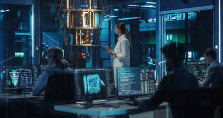 Female Engineer Working on Quantum Computer Hardware, Using Tablet Computer to Access Technical...