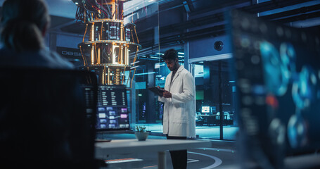 Indian Researcher in a White Lab Coat Using a Tablet in an Advanced Research Center with a Quantum Computer. Office Monitors Performing a Microbiology Test in a Molecular Modelling Software