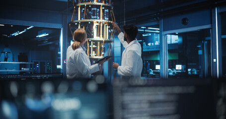 Female and Male Engineers Collaborating on Quantum Computer Development, Discussing a Report on a...