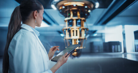 Female Researcher in White Coat Standing Next to a Powerful Quantum Processor, Using a Tablet Computer to Monitor Digital Data. Thoughtful Young Woman is Analyzing Results and Parameters Online
