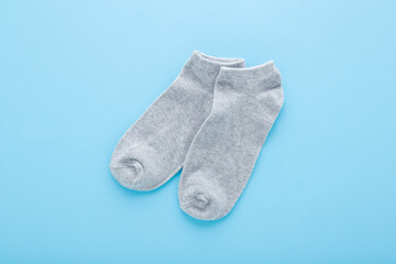 Pair of new light gray short socks on blue table background. Pastel color. Closeup. Top down view.	