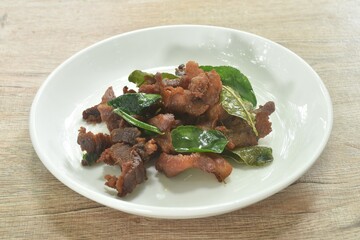 fried crispy salty fermenting pork meat with lemon leaf and chili on plate 