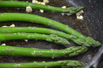 Sautéing Fresh Green Asparagus with Chopped Garlic in a Hot Skillet – Beginning of a Healthy Stir-Fry Recipe