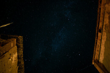 Starry sky seen between the rooftops of old rustic stone houses, typical of traditional Spanish...