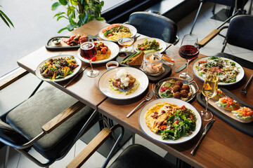 Elegant restaurant table served with diverse gourmet food and assorted drinks for a group meal.