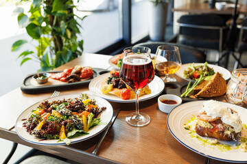 Delicious gourmet lunch with wine glasses and diverse meals in a cozy restaurant setting.