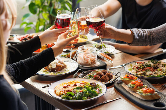 People making a toast with wine at a shared gourmet lunch in a modern restaurant setting.