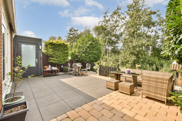 A serene garden patio featuring outdoor seating, potted plants, and a tranquil backdrop of lush...