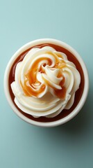 Delicious dessert featuring caramel and whipped cream in a cup on a light blue surface