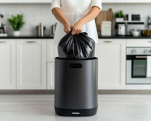 A person is disposing of a black garbage bag into a modern kitchen trash can, emphasizing cleanliness and organization in home environments.