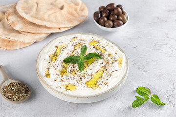 Traditional Middle Eastern appetizer of labneh cheese with olive oil, za'atar, fresh mint, olives and pita bread.