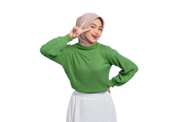 Beautiful smiling Asian woman in a green sweater looking at camera and showing peace sign with fingers isolated on transparent background