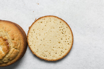 Overhead view of vanilla cake layers on a white countertop, top view of vanilla cake slices about to be assembled, process of making layered cake
