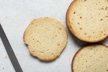 Overhead view of vanilla cake layers on a white countertop, top view of vanilla cake slices about to be assembled, process of making layered cake
