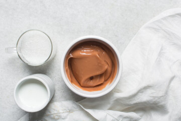 Overhead view of nigerian akamu being made in a white bowl, pap akamu or ogi in a white bowl, top view of nigerian guinea corn pudding in a white ramekin