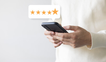 close up on customer man hand pressing on smartphone screen with gold five star rating feedback...