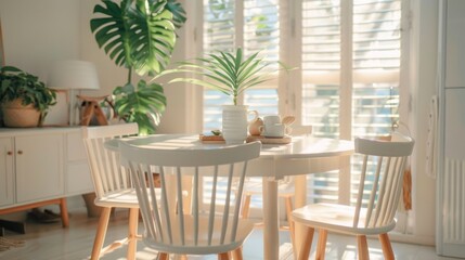 Obraz premium Bright dining space with white table set, leafy plant and warm daylight