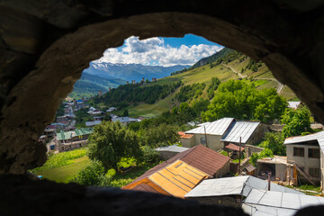 Breathtaking view of mestia village and surrounding caucasus mountains from ancient svaneti defensive tower in upper svaneti region, georgia, under a beautiful blue sky with white clouds