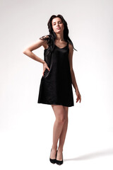 Model posing in a black dress showcasing elegance in a simple studio setting during daylight