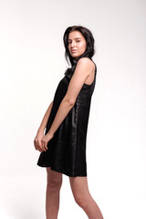 Model showcases elegant black dress against simple backdrop during studio shoot in afternoon light