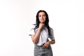 Woman posing confidently with hand on chin in a minimalist studio setting during daylight hours