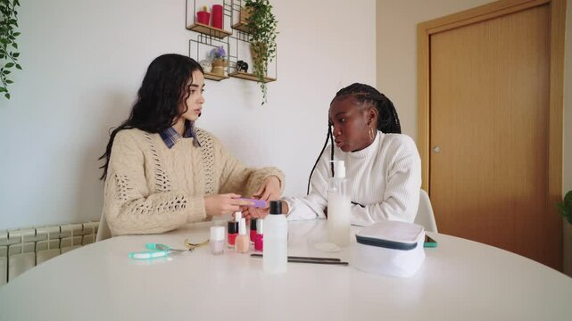 Woman painting her friend's nails at home