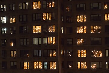 Festive holiday lights illuminate apartment building windows at night.