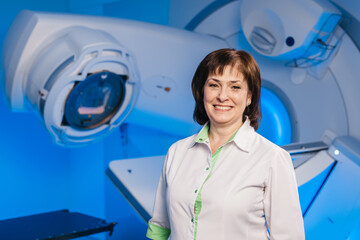 A medical professional stands in front of a linear accelerator for radiotherapy. A concentration of...