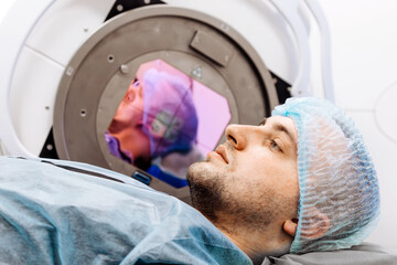 A young man undergoing radiation therapy for cancer in a state-of-the-art oncology clinic using a...
