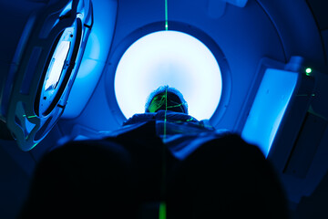 A young man undergoing radiation therapy for cancer in a state-of-the-art oncology clinic using a...
