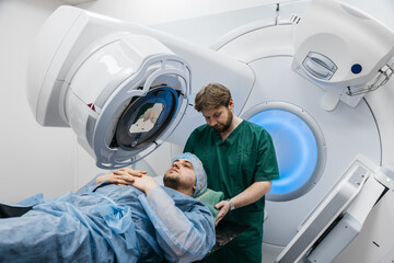 In a modern oncology clinic, a man is prepared for radiation therapy on a modern linear...
