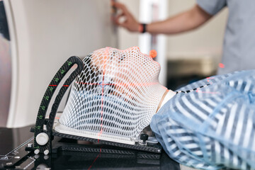 Specialists are preparing the young woman for radiation therapy by putting a special mask on him...