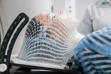 Specialists are preparing the young woman for radiation therapy by putting a special mask on him...