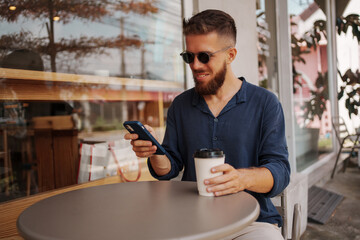 A man is enjoying his coffee while using a smartphone in a cozy cafe atmosphere