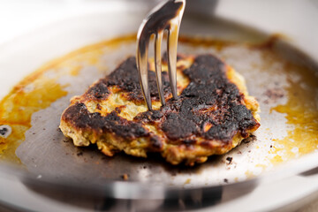 Picking up a burnt pancake from the pan using a fork. Macro shot