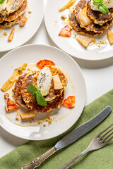 Cottage cheese pancakes with cream cheese, orange, honey and mint on a white plate and background. Healthy, dietary breakfast. Top view