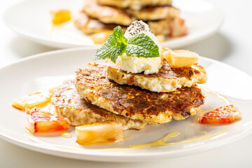 Healthy, dietary breakfast. Cottage cheese pancakes with cream cheese, orange, honey and mint on a white plate and background.