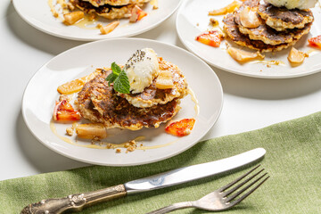 Cottage cheese pancakes with honey, orange, mint and cream are decorated with mint on a white plate. The concept of a delicious and healthy dietary breakfast. Close-up.