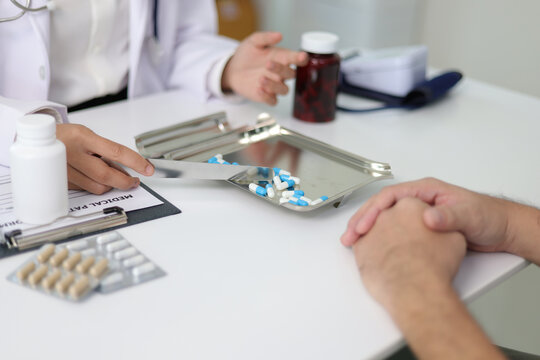 Doctor preparing prescription drugs for patient in clinic. Female doctor counting and prepare prescription capsules for her patient during a medical consultation in a clinic.