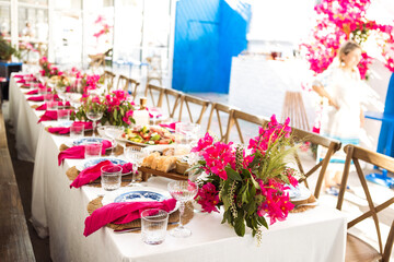 A set festive table in the open air. The table is decorated with candles and flowers