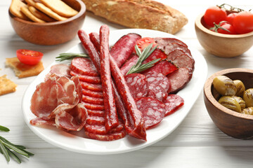 Different smoked sausages slices served on white wooden table, closeup
