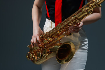 Professional musician with saxophone on grey background, closeup