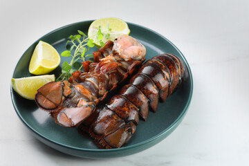 Raw lobster tails, lime and microgreens on white marble table, closeup