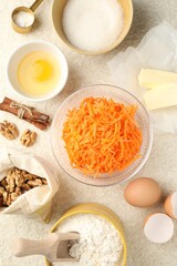 Different ingredients for making carrot cake on beige textured table, flat lay