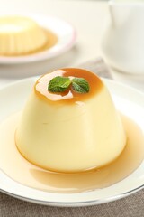 Delicious pudding with caramel sauce and mint on table, closeup