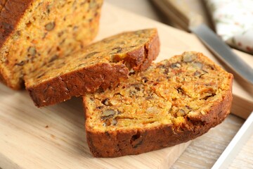 Cut homemade carrot cake with nuts and knife on wooden table, closeup