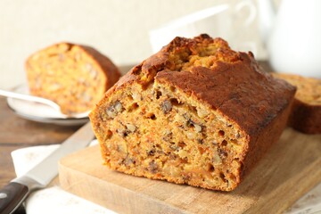 Cut homemade carrot cake with nuts and knife on table, closeup